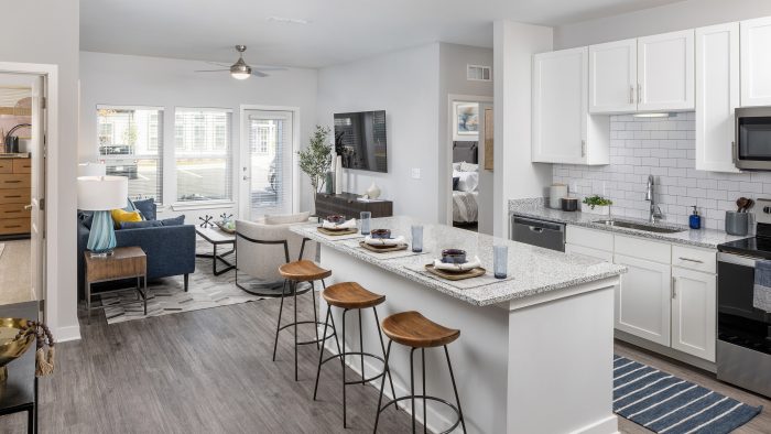 Kitchen in home at Story Mundy Mill with white cabinets and stainless steel appliances and kitchen island with bar stools