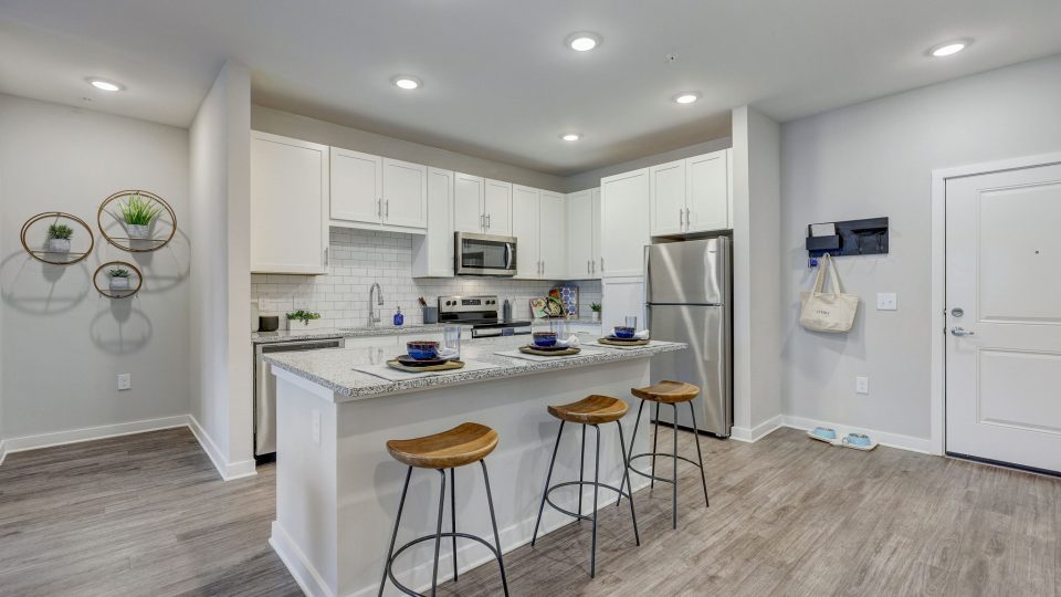 a clean and white kitchen with stainless steel appliances at The Story Mundy Mill